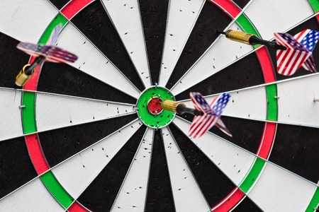 Dart arrow hitting in the red target center of dartboardの写真素材