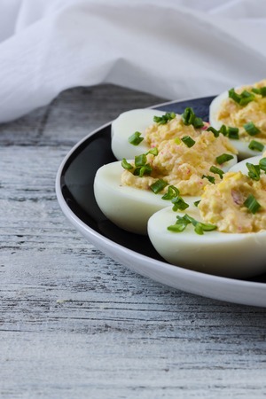 Home eggs stuffed with cheese and crab sticks topped with green onionsの写真素材