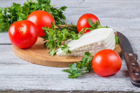 White brine cheese, knife, parsley, tomatoes on a wooden boards backgroundの写真素材