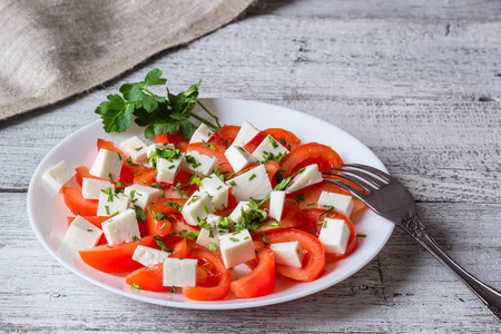 Fresh salad with tomato, mozzarella and herbs on white wooden backgroundの写真素材