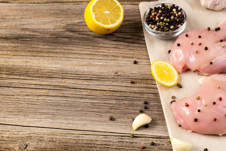 Raw chicken breasts with lemon pepper and garlic on backgroundの写真素材