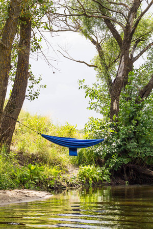 Blue hammock in greenery near the river. View from the riverの写真素材