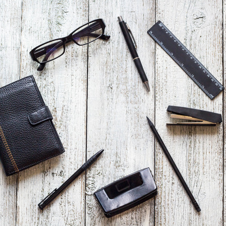 Black and white still life: opened blank notepad, notebooks, pen, pencil and glasses. Top view, flat...