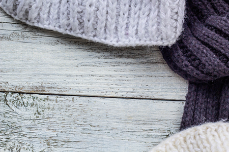 Fragment of knitting clothes on white wooden background.