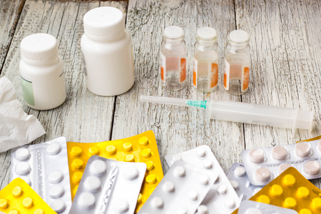 Lot of medicines, syringe, thermometer and pills on white wooden backgroundの写真素材