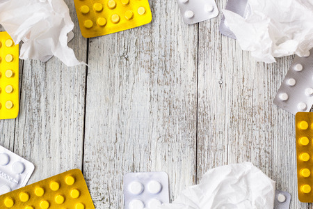 Pills border background. Vitamins, tablets, pills in blister pack and crumpled handkerchiefs on white wooden background. Top view. Copy space for textの写真素材