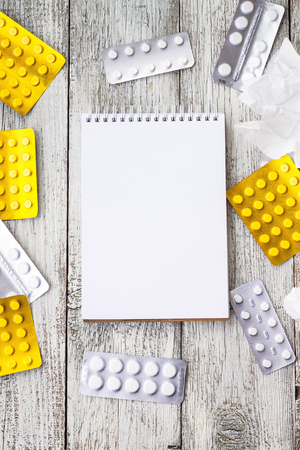pills with notebook on white wooden background. Copyspaceの写真素材