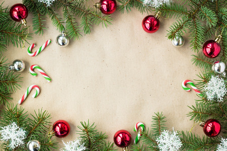 Festive christmas border with red and silver balls on fir branches and snowflakes on rustic beige background with copyspace and pen.の写真素材