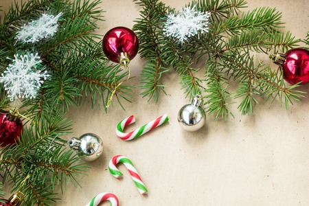 Festive christmas border with red and silver balls on fir branches and snowflakes on rustic beige...