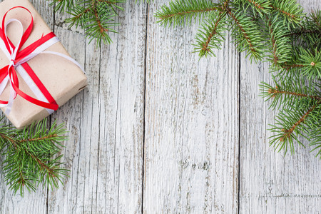 Christmas background with gift and fir tree on white wooden table. Top view with copy space. Gift wrappingの写真素材