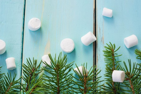 Christmas border with branch of fir tree and marshmallows on wooden background. Top view copy spaceの写真素材