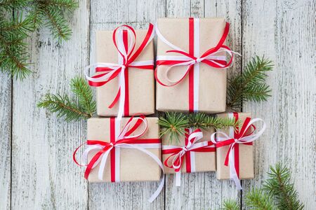 Christmas gift boxes with red and white ribbon on wooden background with Fir branches. Xmas and Happy New Year composition. Flat lay, top viewの写真素材