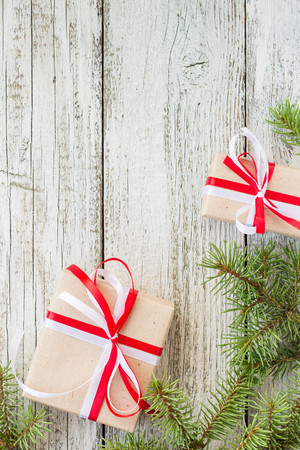 Border of Christmas gift boxes and fir tree branch on wooden table. Top view with copy spaceの写真素材