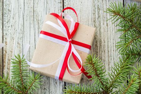 Christmas gift boxes with red and white ribbon on wooden background with Fir branches. Xmas and Happy New Year composition. Flat lay, top viewの写真素材