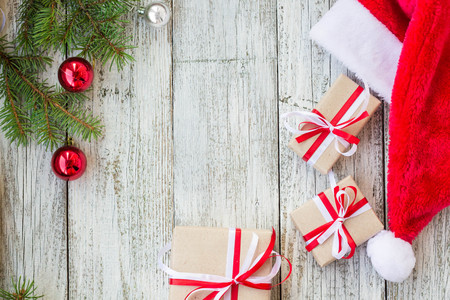 Christmas holiday wooden background with fir branches, Santa hat and gift boxes. top view, copy spaceの写真素材