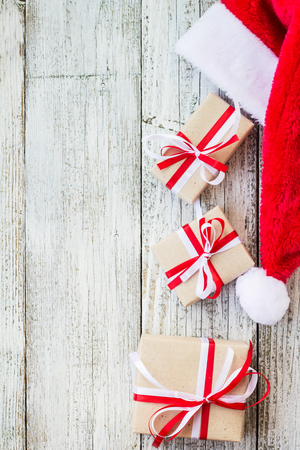 Top view of santa hat with christmas gift boxes on white wooden background. Free space for textの写真素材