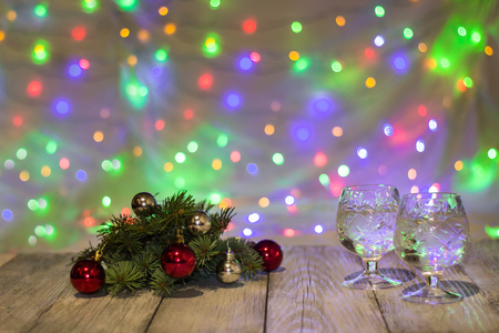 Two glasses of christmas champagne with christmas tree decorated of red and silver balls against light bokeh background.の写真素材