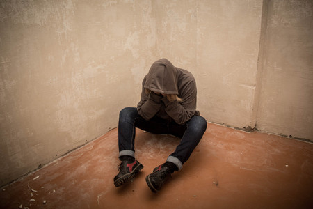 Portrait of man sad, drug addict man sitting on the floor in corner.