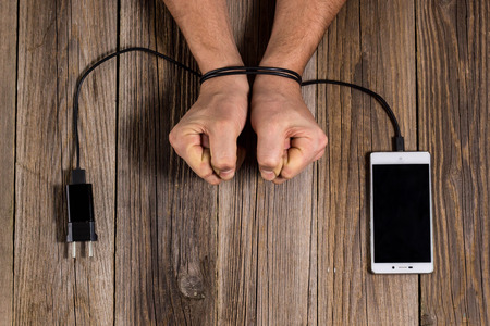 human hands are associated with charging of the phone as a symbol of dependence on technology and workaholism.の写真素材