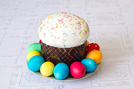 Easter cake with glace icing and easter eggs on white table cloth background.