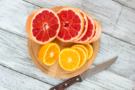 Sliced orange and lemon on a wooden board and knife.の写真素材