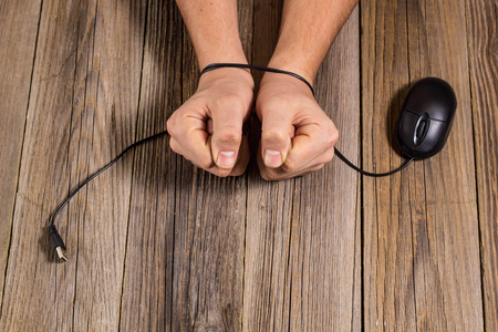 human hands bound by wire computer mouse as a concept the dependence of man on modern technology, Internet.の写真素材