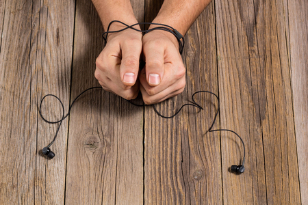 hands of man tied with phone headset, as the concept of man's dependence on music, technology.の写真素材