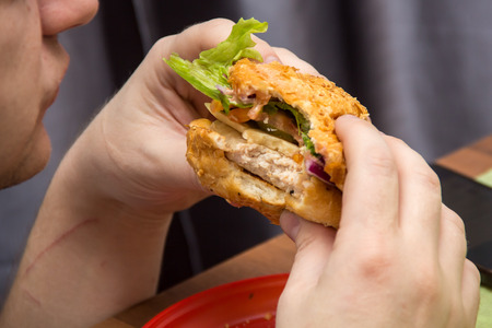 Close Up Of Man Hands Holding Delicious Burger and eating it. Fast food conceptの写真素材