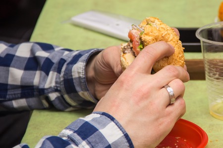 Close Up Of Man Hands Holding Delicious Burger and eating it. Fast food conceptの写真素材