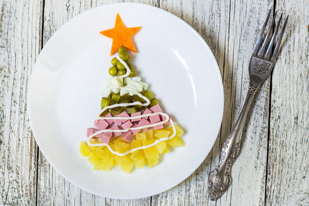 Christmas tree from a salad olivier in plate on a white wooden table. Top view with a copy space.の写真素材