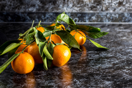 many orange tangerines with green leaves on dark background. Copy space.の写真素材