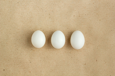 Top view of three white eggs on rustic background with copyspace
