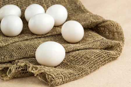 Fresh white eggs on burlap textile at rustic background with copy space. Rural still life, natural organic healthy food.の写真素材