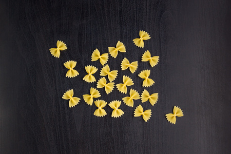 A pile of farfalle pasta on dark black backgroundの写真素材