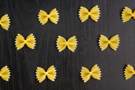 Pattern of A pile of farfalle pasta on dark black backgroundの写真素材