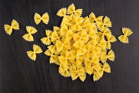A pile of farfalle pasta on dark black backgroundの写真素材