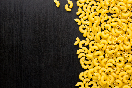 Border of A pile of pasta horns on dark black background with copyspaceの写真素材