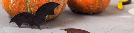 Banner of orange pumpkin and paper bats on white table, halloween concept.