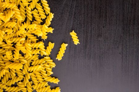 Border of A pile of pasta spiral fusilli on dark black background with copyspaceの写真素材