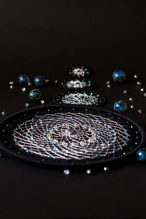 process of creating Dream catcher with feathers threads and beads rope hanging. Dreamcatcher handmade on black backgroundの写真素材