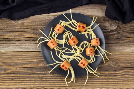 spaghetti with sausages in the form of spiders. Happy kid food for Halloween party on wooden background. Top view with copyspaceの写真素材