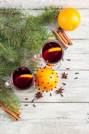 christmas hot mulled wine with cinnamon orange and anise on white wooden background with treeの写真素材