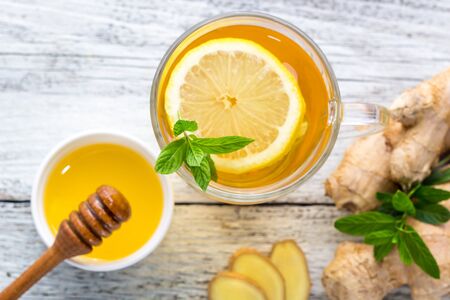 Ginger tea with lemon mint and honey on a white wooden background. Hot healthy winter drink with copy spaceの写真素材