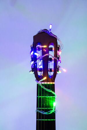 Acoustic guitar wrapped by colorful garland. christmas and new year music gift as background