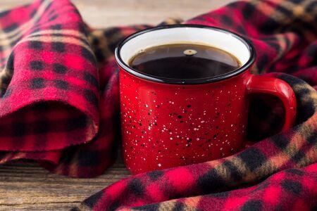hot coffee in red cup and cozy plaid on natural wooden backgroundの写真素材
