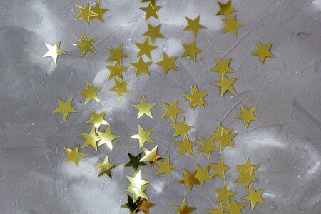Gold confetti stars on a grey christmas background.の写真素材
