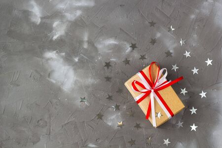 gift box of craft paper with bow and silver star decorations on grey background. Celebration conceptの写真素材