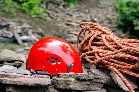Rope access tools: hard hat, rope, carabiner. Mountaineering equipment on rocks against a background of rocks and greeneryの写真素材