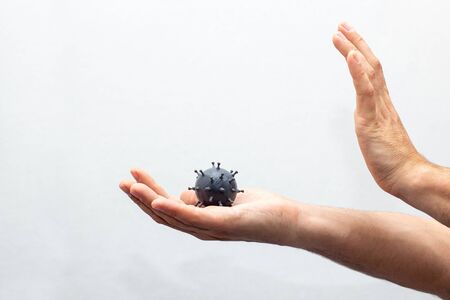 A human hands hold a mockup of a grey coronavirus molecule. concept of the protection of covid-19 indoor on white backgroundの写真素材