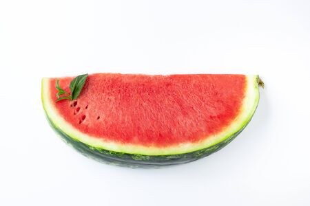 Sliced of fresh red ripe watermelon with green leaves of mint on white backgroundの写真素材